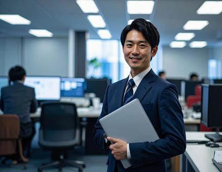 オフィスでPCを持って微笑む社員 オフィスでPCを持って微笑む社員の写真