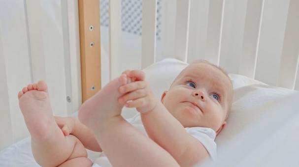 自分の足を掴み見上げる赤ちゃん 自分の足を掴み見上げる赤ちゃん 赤ちゃん,かわいい,仰向けの写真素材