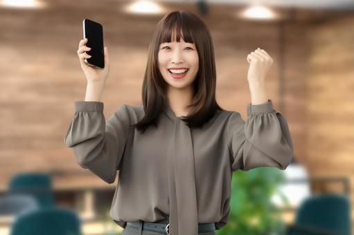 スマホを持ってガッツポーズをする女性 女性,スマホ,スマートフォンの写真素材