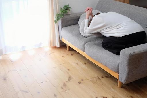 ソファーで悩む40代女性 後ろ姿,ショック,不安の写真素材