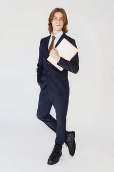 ノートパソコンを抱えてカメラ目線のスーツの男性の全身 男性,外国人,欧米人の写真素材