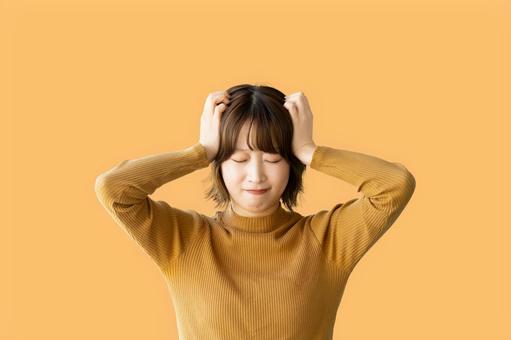 頭を抱えて困る女性(オレンジ背景) 頭を抱えて困る女性(オレンジ背景) 女性,困る,悩むの写真素材