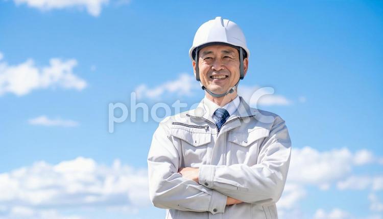 青空の下で笑顔の日本人中年男性建設作業員 作業服,男性,中年の写真素材