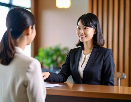 顧客と話をするスーツ姿の女性 顧客と話をするスーツ姿の女性の写真