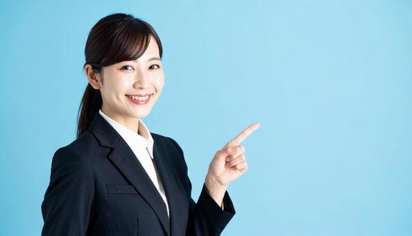 笑顔で指差すビジネスウーマンの写真