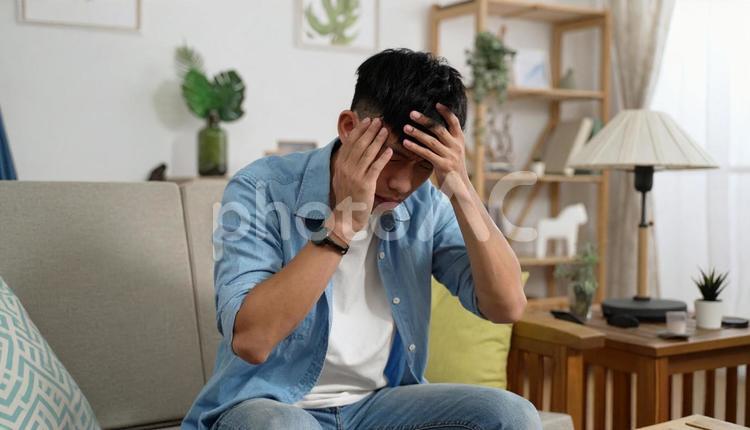 頭を抱える男性の室内ポートレート 人物,男性,20代の写真素材
