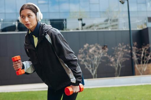 ダンベルを持ってジョギングする女性 ダンベルを持ってジョギングする女性 女性,ヘッドフォン,人物の写真素材