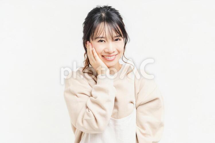 頬に手を当てる笑顔の若い女性 女性,頬,笑うの写真素材