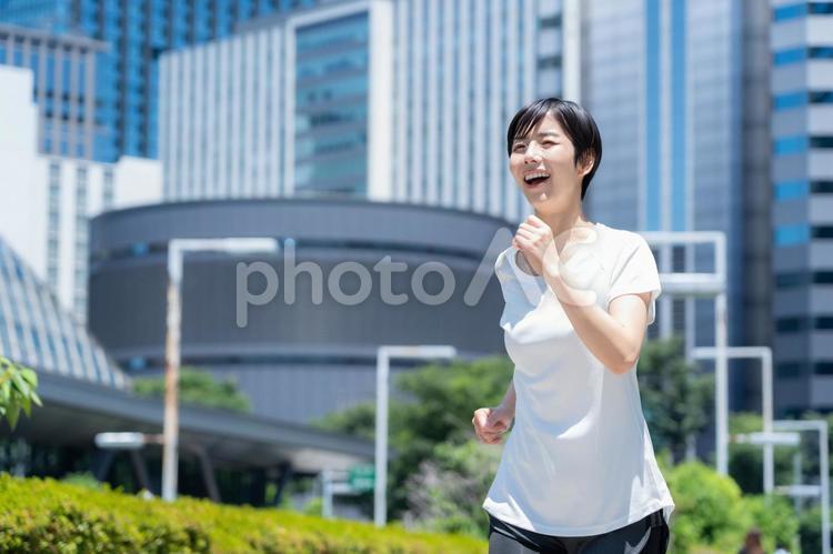 オフィス街をジョギングする若い女性 ランニング,ジョギング,フィットネスの写真素材