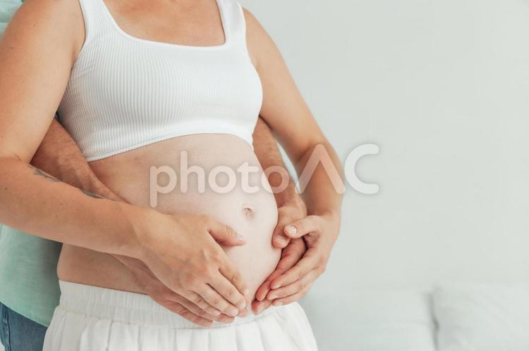 妊婦のお腹を後ろから触る男性の手元 手元,水色,女性の写真素材