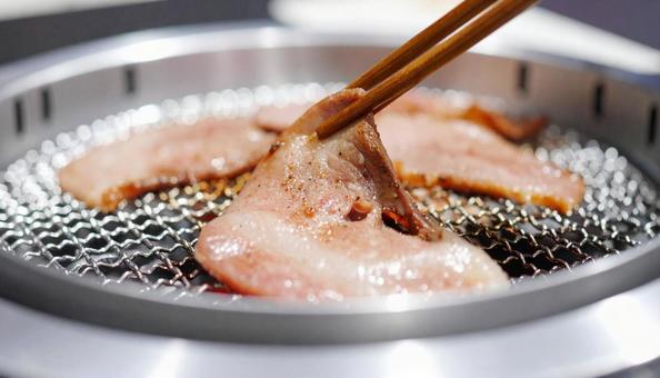 焼肉を鉄板で焼いて箸ですくう 焼肉を鉄板で焼いて箸ですくうの写真