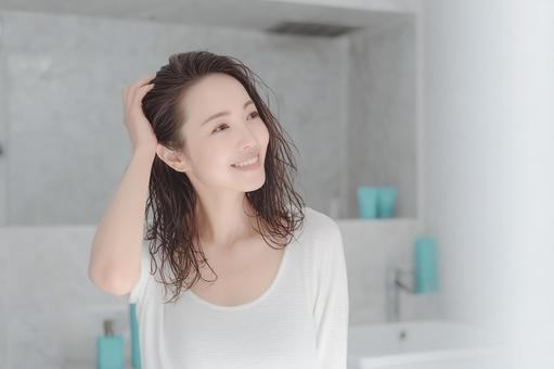 シャンプー後にヘアケアするミドル女性 シャンプー後にヘアケアするミドル女性の写真