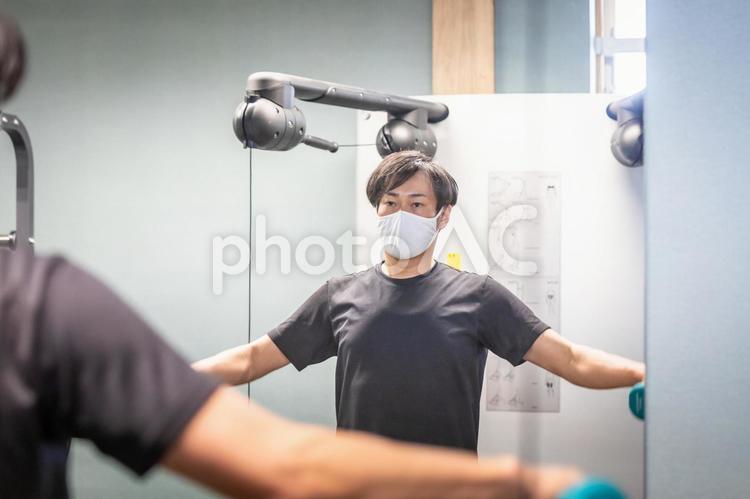 スポーツジムでダンベルを使う男性（マスク） ダンベル,負荷,筋トレの写真素材