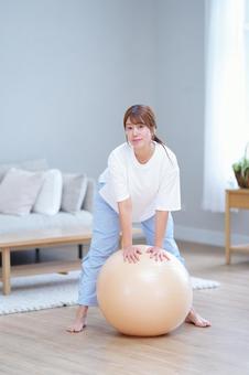 足を広げボールを押す女性の写真