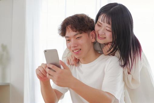 スマホを見ながら笑い合う仲良しカップル スマホ,スマートフォン,携帯電話の写真素材