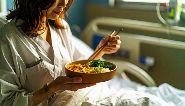 ベッドに座って食事をする女性の患者 ベッドに座って食事をする女性の患者の写真