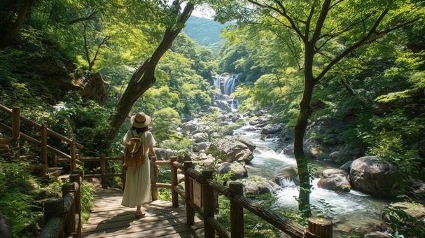 夏の渓流沿いの遊歩道に立つ若い日本人女性 夏の渓流沿いの遊歩道に立つ若い日本人女性の写真