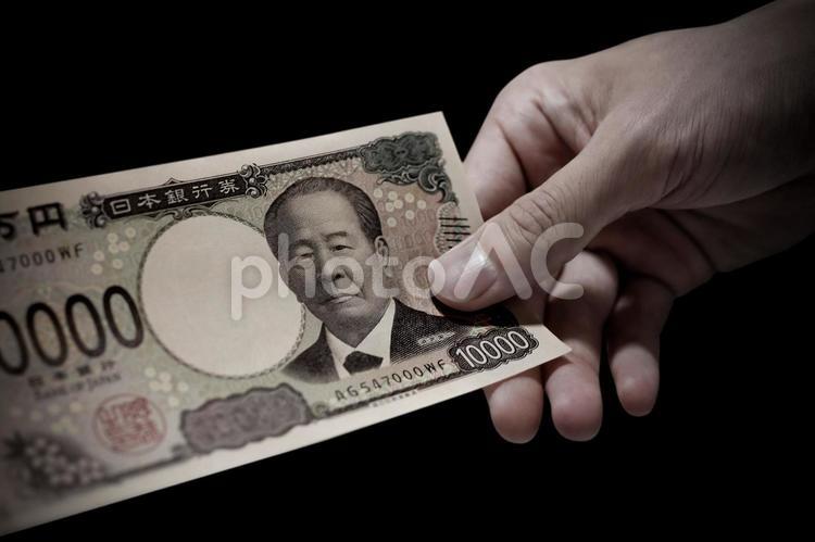 一万円札を持つ手のネガティブなイメージ ネガティブ,裏金,暗いの写真素材