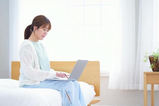 ベッドでパソコン作業する女性 女性,ノートパソコン,座るの写真素材
