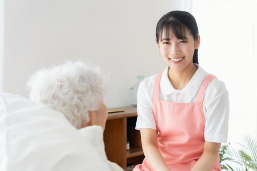 寝ているシニア女性を介護をする介護士 寝ているシニア女性を介護をする介護士 介護,介護士,シニアの写真素材