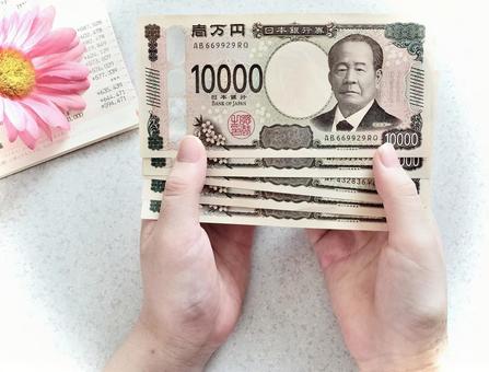 女性が通帳を広げ、手に五万円を持っている 女性が通帳を広げ、手に五万円を持っている お札,一万円札,通帳の写真素材