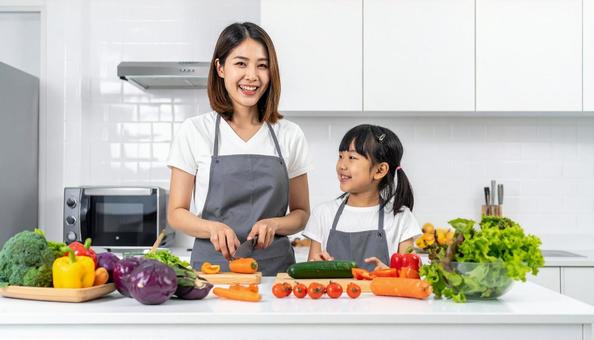 キッチンで料理をする母親と女の子 キッチンで料理をする母親と女の子の写真