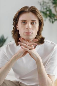 カメラ目線で両手を組んで椅子に座る男性 男性,外国人,欧米人の写真素材