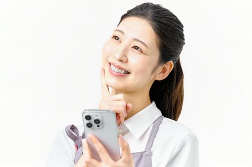 スマホを持ち考える笑顔の主婦 スマホを持ち考える笑顔の主婦 主婦,スマホ,考えるの写真素材