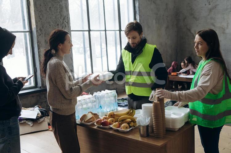 ボランティアから炊き出しをもらう女性 炊き出し,ボランティア,男性の写真素材