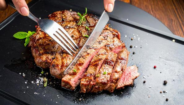 鉄板焼きのステーキをナイフで切る 鉄板焼きのステーキをナイフで切るの写真