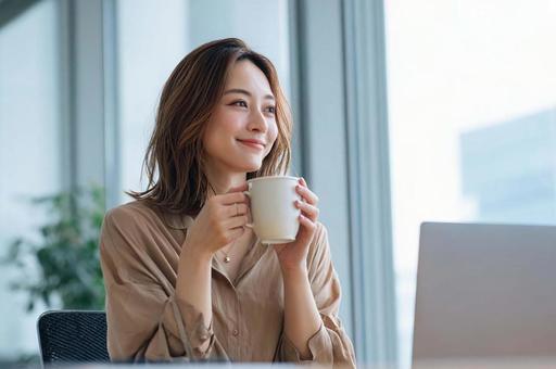 デスクで一息つくビジネス女性 デスクで一息つくビジネス女性の写真