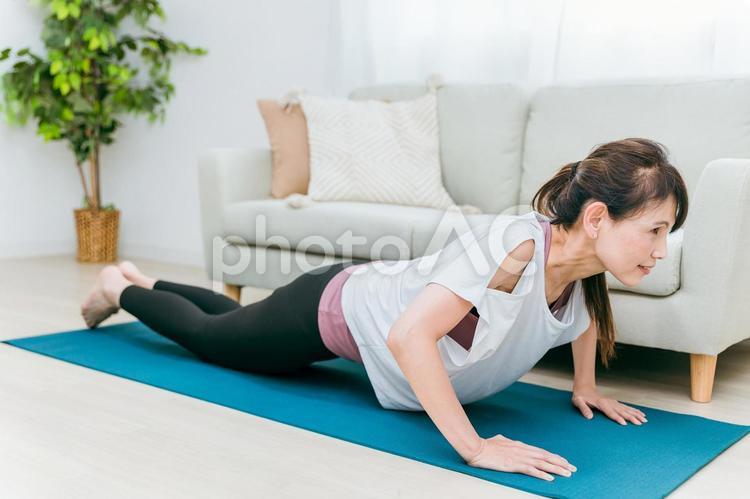 部屋で腕立て伏せをするミドル世代の女性 腕立て伏せ,腕立て,筋トレの写真素材