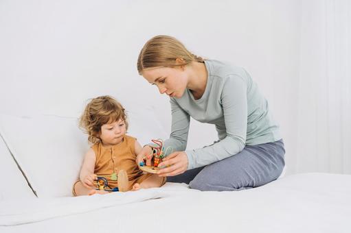 ベッドの上で子供に玩具を見せる女性 ベッドの上で子供に玩具を見せる女性 親子,母子,赤ちゃんの写真素材