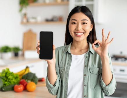 スマートフォンを手にOKサインの女性 スマートフォンを手にOKサインの女性の写真
