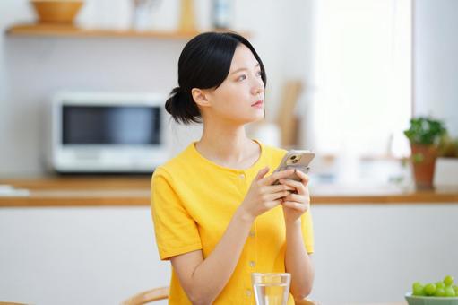 両手でスマートフォンを持つ真剣な顔の女性 女性,スマートフォン,持つの写真素材