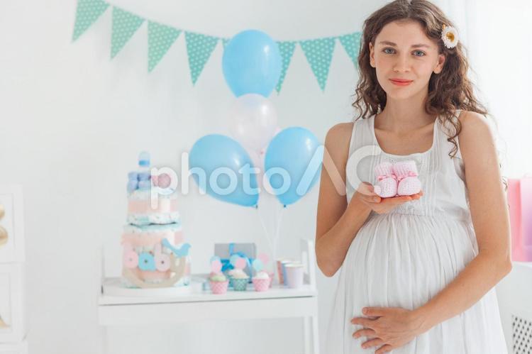 ベビーシューズを持ってカメラ目線の妊婦さん 女性,人物,風船の写真素材