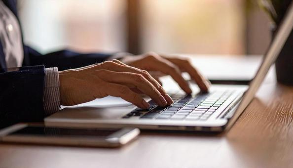 デスクワーク　パソコンに両手で入力する手の写真