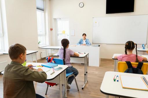 座って授業をする先生と生徒の後ろ姿 女性,女の子,男の子の写真素材