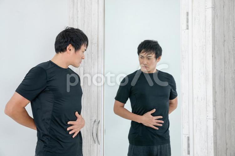 鏡の前でボディチェックする男性 ウエスト,腹筋,お腹の写真素材