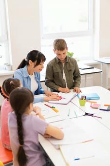 添削する先生と生徒たち 女性,女の子,男の子の写真素材