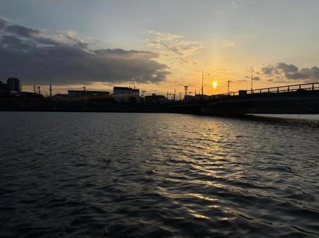 夕日でオレンジ色に染まる水面 夕日でオレンジ色に染まる水面の写真