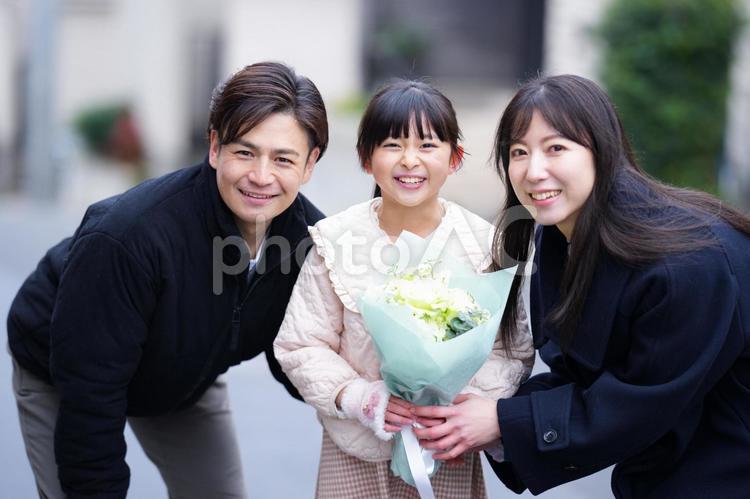 花束を持った女の子とかがんだ家族 家族,男性,女性の写真素材