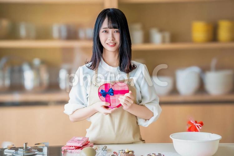 ハートのチョコを見せる若い女性パティシエ バレンタイン,バレンタインデー,チョコの写真素材