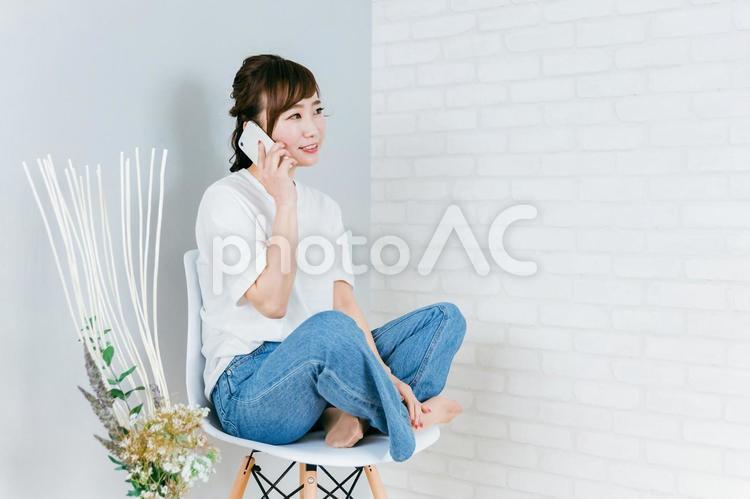 椅子に座りながらスマホを使うアジア人女性 スマホ,電話,通話の写真素材