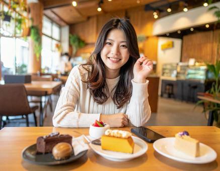 カフェでスイーツを楽しむ女性 カフェでスイーツを楽しむ女性の写真