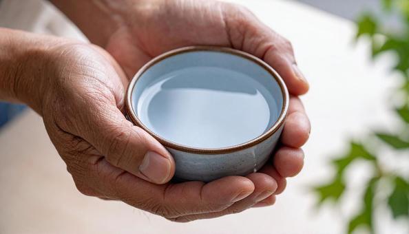 一杯の飲み物を手に取る日本人男性の手の写真