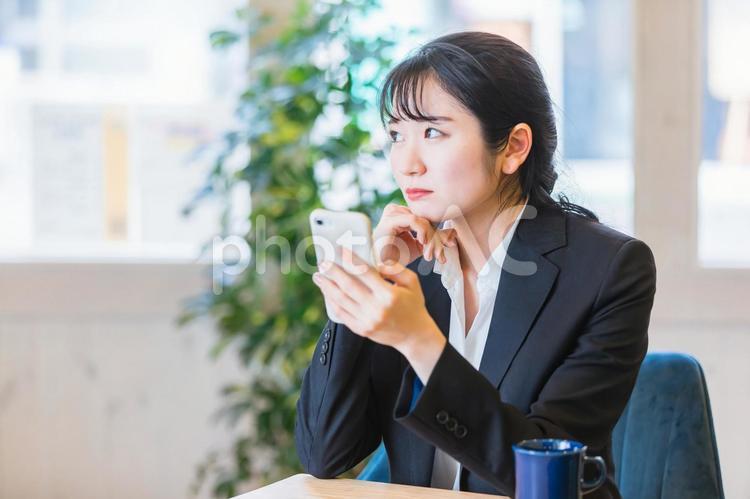 スマホを見ながら困る女性 スマホ,ストレス,困るの写真素材