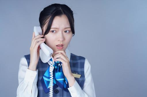制服姿の女性が指を唇に当てて考えるの写真