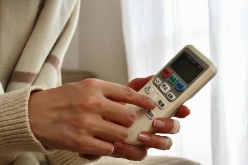 リモコンを持つ女性 エアコン,暖房,リモコンの写真素材