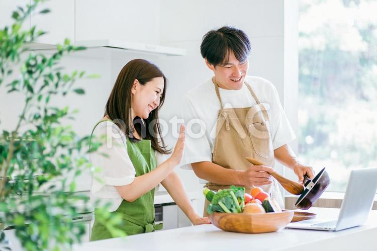 家事を手伝う男性と女性（パソコン） キッチン,夫婦,パソコンの写真素材